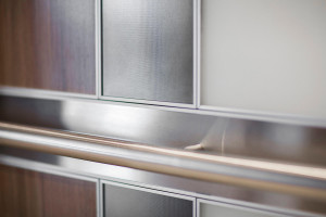 FSRT694 Интерьер лифта Levele-101 с индивидуальной компоновкой панелей; панели из стекла vivichrome chromis с белой прослойкой и отделкой opalex, плавленый графит с льняной отделкой, нержавеющая сталь с матовой отделкой, индивидуальный шпон; Круглый поруч